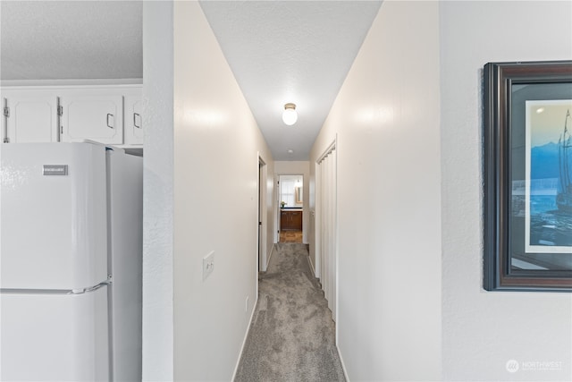 hall with light carpet and a textured ceiling