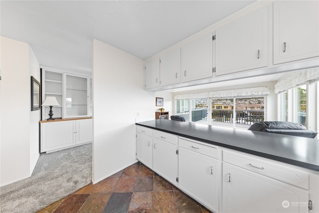 kitchen featuring white cabinetry and dark carpet