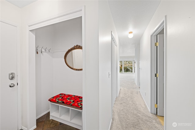 hallway with a textured ceiling and dark carpet