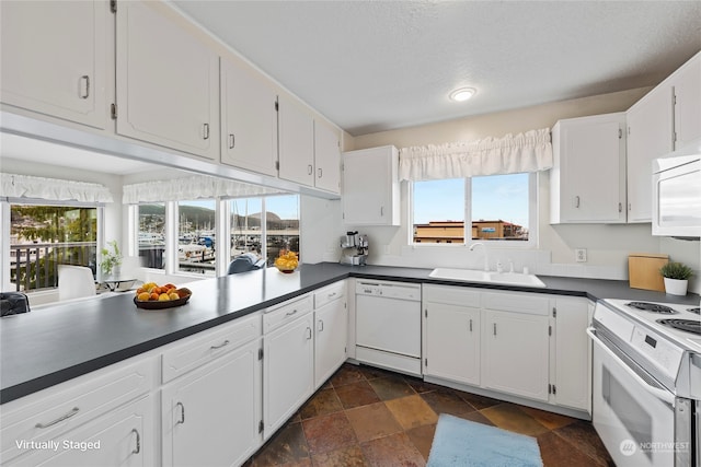 kitchen with white appliances, a healthy amount of sunlight, white cabinetry, and sink