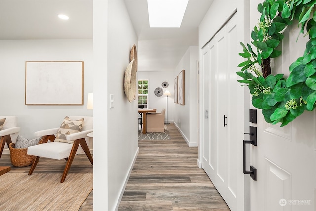 hall featuring hardwood / wood-style flooring and a skylight