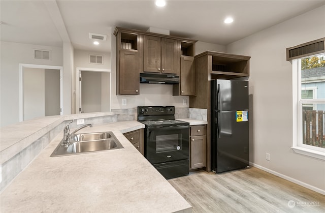 kitchen with sink, black appliances, dark brown cabinets, and light hardwood / wood-style floors