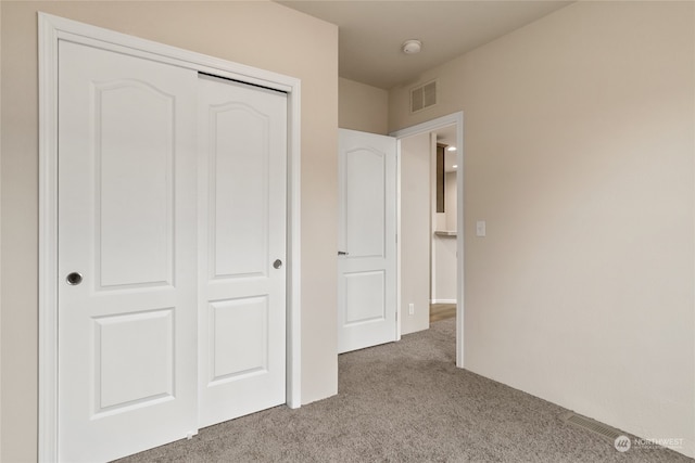 unfurnished bedroom with light carpet and a closet