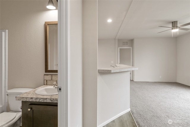 bathroom with vanity, toilet, wood-type flooring, and ceiling fan