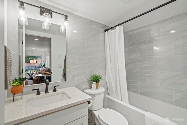 full bathroom with shower / bath combo with shower curtain, vanity, toilet, and tile walls