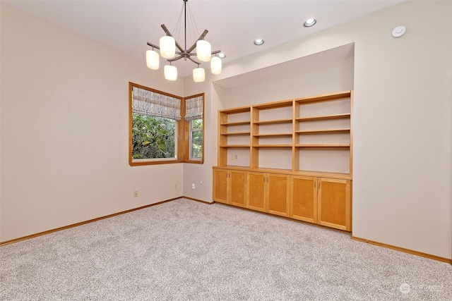 carpeted empty room featuring a chandelier