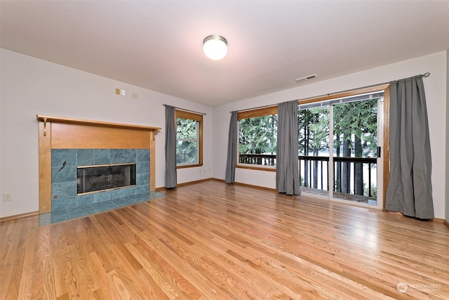 unfurnished living room with a tile fireplace and light hardwood / wood-style floors