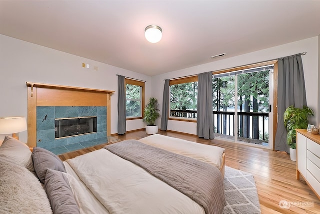 bedroom featuring a fireplace, access to outside, and light hardwood / wood-style floors