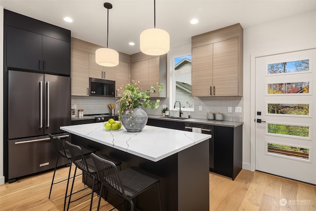 kitchen with sink, decorative light fixtures, a center island, a kitchen breakfast bar, and stainless steel built in fridge