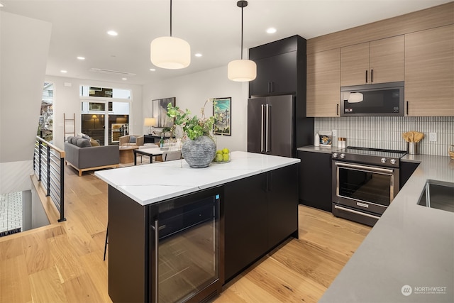 kitchen featuring high end appliances, wine cooler, light stone countertops, a kitchen island, and decorative light fixtures