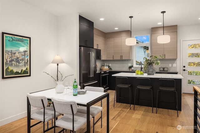 kitchen with stainless steel range with electric cooktop, a kitchen breakfast bar, hanging light fixtures, a center island, and high end fridge