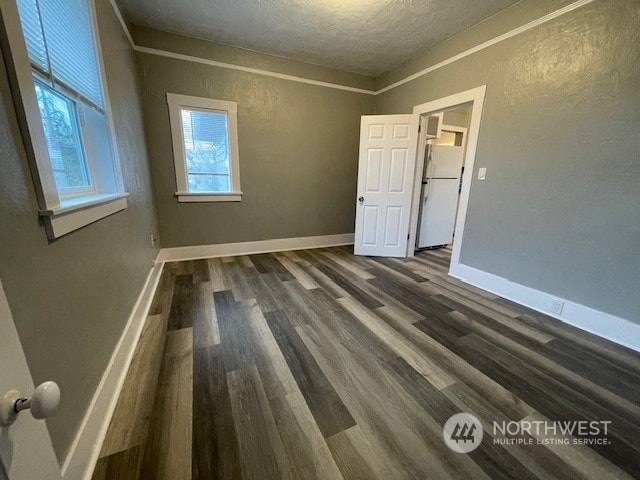 spare room with a textured ceiling, crown molding, and dark hardwood / wood-style floors