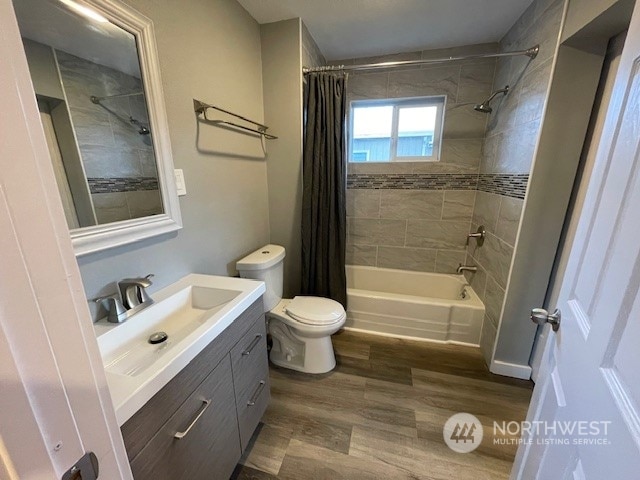 full bathroom with vanity, toilet, hardwood / wood-style flooring, and shower / tub combo with curtain