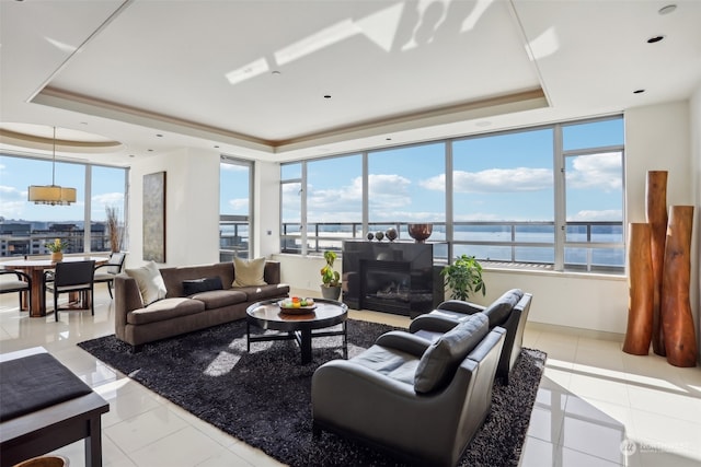 tiled living room featuring a water view and a tray ceiling