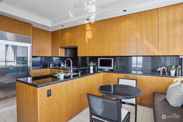 kitchen with tasteful backsplash, light tile patterned floors, and built in refrigerator