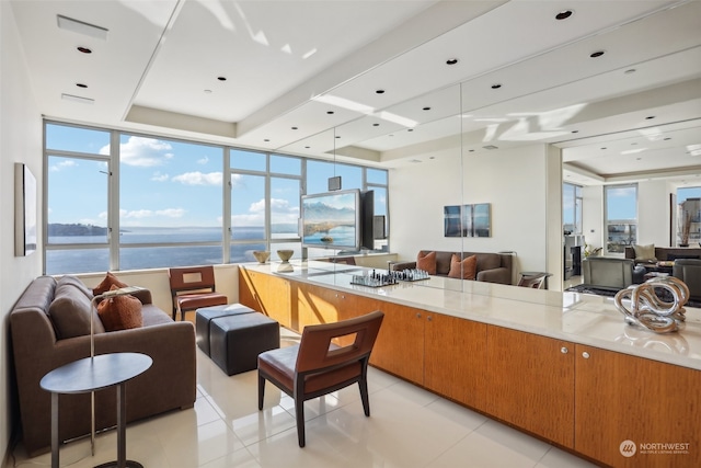 kitchen featuring a water view, a healthy amount of sunlight, light tile patterned flooring, and a wall of windows