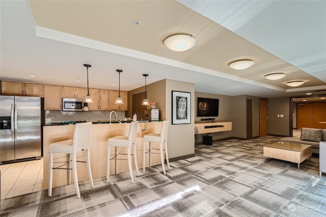 kitchen with appliances with stainless steel finishes, sink, a raised ceiling, decorative light fixtures, and decorative backsplash