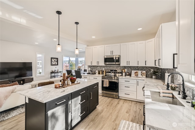 kitchen with a center island, light hardwood / wood-style floors, stainless steel appliances, pendant lighting, and white cabinets