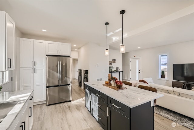 kitchen with a kitchen island, light hardwood / wood-style flooring, decorative light fixtures, white cabinetry, and stainless steel refrigerator