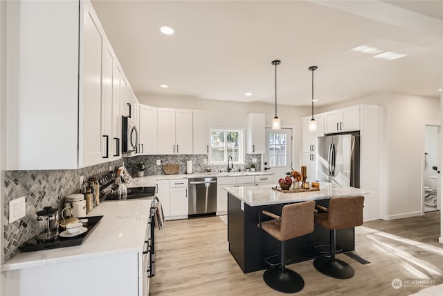 kitchen featuring stainless steel appliances, a center island, pendant lighting, and white cabinets