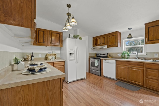 kitchen with white appliances, vaulted ceiling, sink, pendant lighting, and light hardwood / wood-style flooring