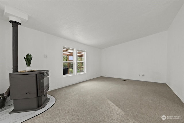 unfurnished living room with carpet floors and a wood stove