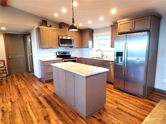 kitchen featuring lofted ceiling, a kitchen island, hanging light fixtures, stainless steel appliances, and sink