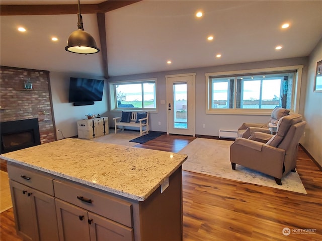 kitchen with light stone countertops, a wealth of natural light, dark wood-type flooring, and pendant lighting