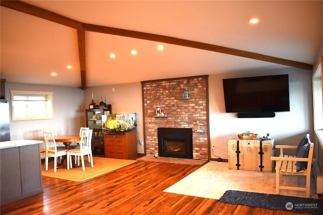 living room with hardwood / wood-style floors, vaulted ceiling with beams, and a brick fireplace