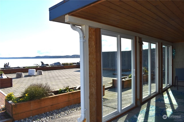 doorway featuring a water view and wooden ceiling