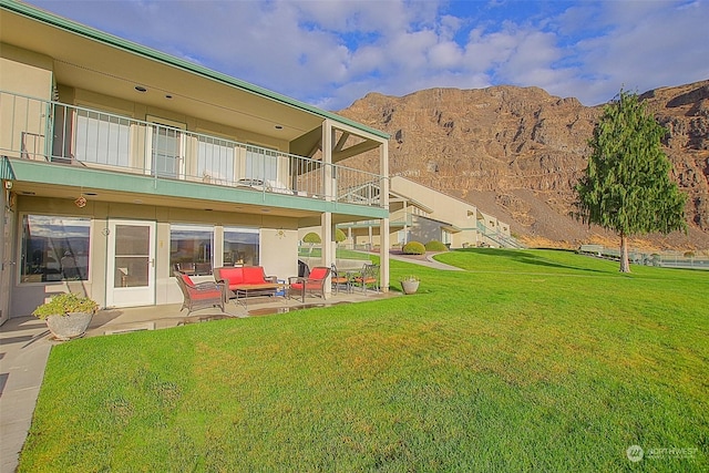 exterior space with an outdoor living space, a balcony, a mountain view, a yard, and a patio