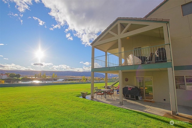 view of yard featuring a water view, a patio, and a balcony