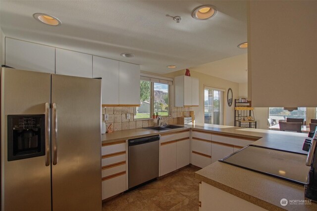 kitchen with a sink, recessed lighting, white cabinetry, decorative backsplash, and appliances with stainless steel finishes