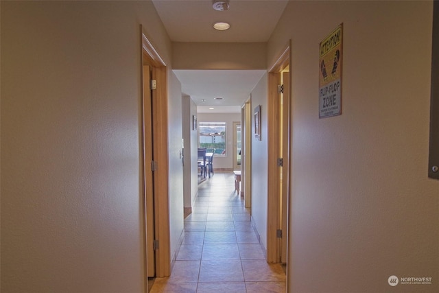 corridor featuring baseboards and light tile patterned floors