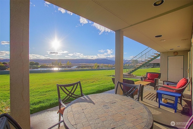 view of patio with stairway, outdoor dining space, and a water view