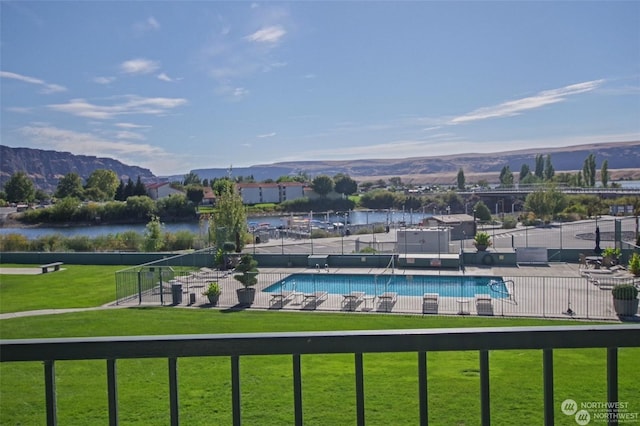 pool featuring fence, a water and mountain view, and a yard