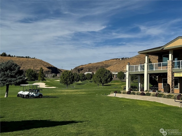 view of yard with a balcony, a mountain view, and view of golf course