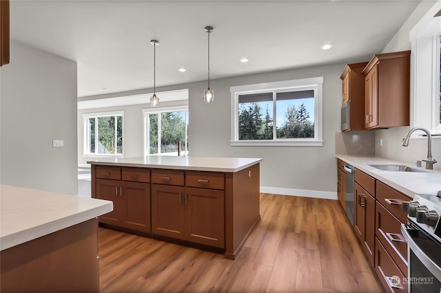 kitchen featuring a kitchen island, hardwood / wood-style flooring, sink, decorative light fixtures, and appliances with stainless steel finishes