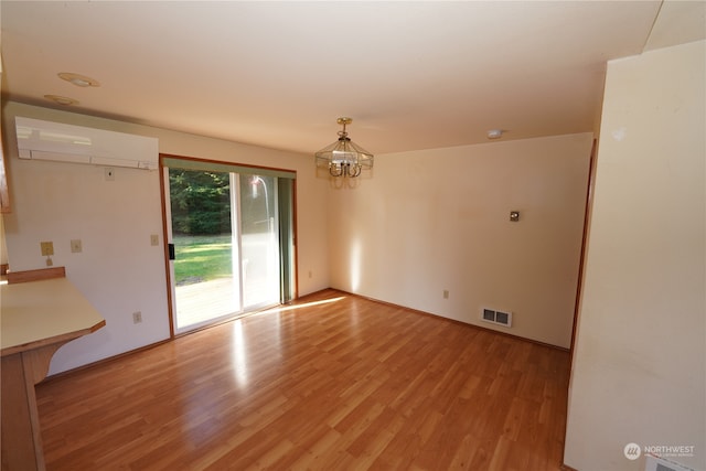 interior space with an AC wall unit, light hardwood / wood-style flooring, and a notable chandelier