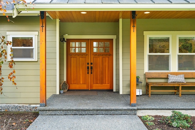 entrance to property featuring a porch and metal roof