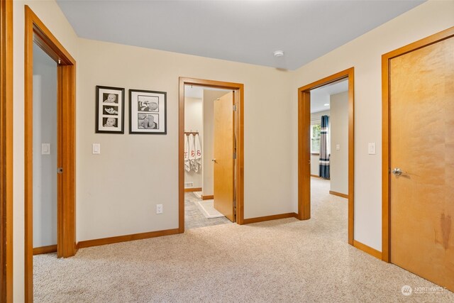 corridor with light colored carpet and baseboards