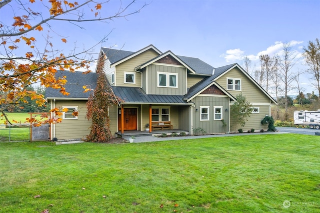 view of front facade with covered porch, a front lawn, board and batten siding, and fence