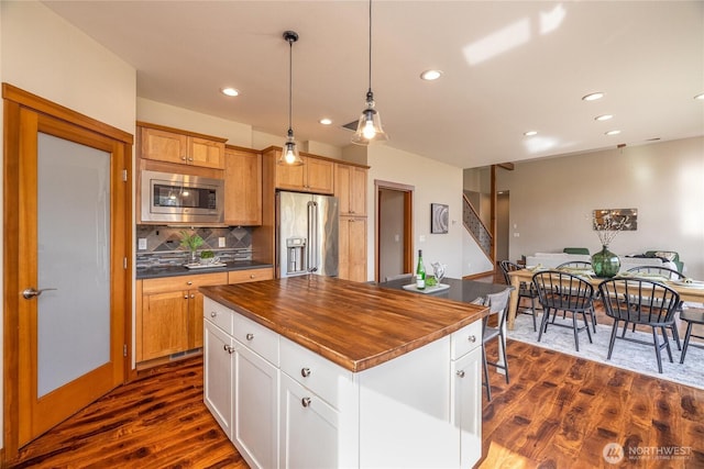 kitchen featuring dark wood-style floors, wood counters, appliances with stainless steel finishes, backsplash, and recessed lighting