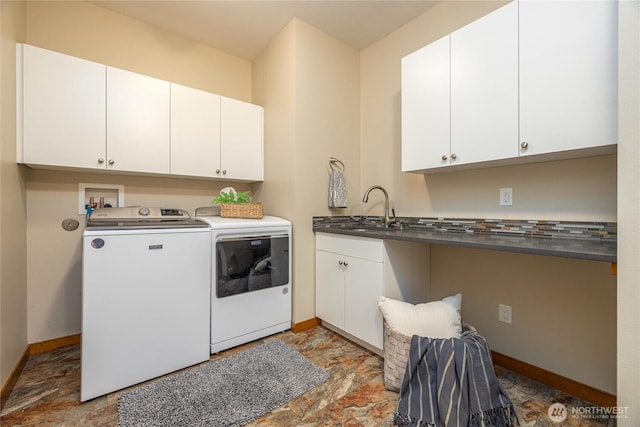 clothes washing area with cabinet space, stone finish flooring, a sink, independent washer and dryer, and baseboards