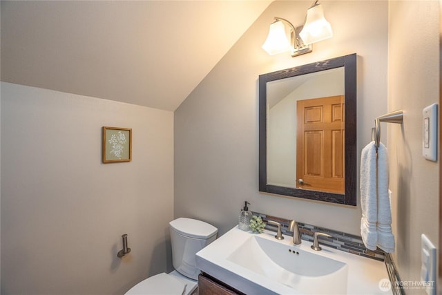 bathroom with toilet, lofted ceiling, and vanity