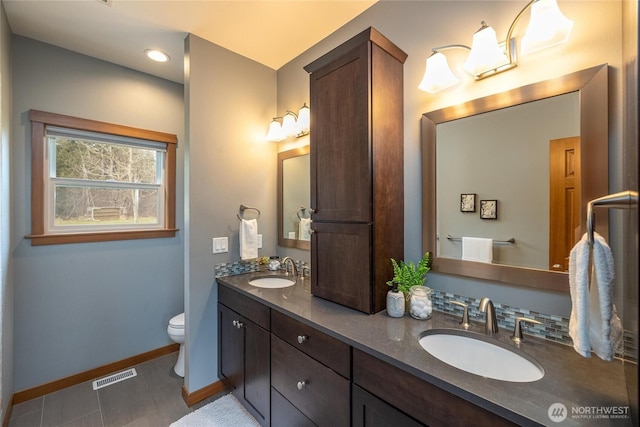 full bath featuring toilet, a sink, visible vents, and baseboards