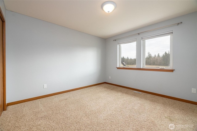 spare room featuring carpet floors, visible vents, and baseboards