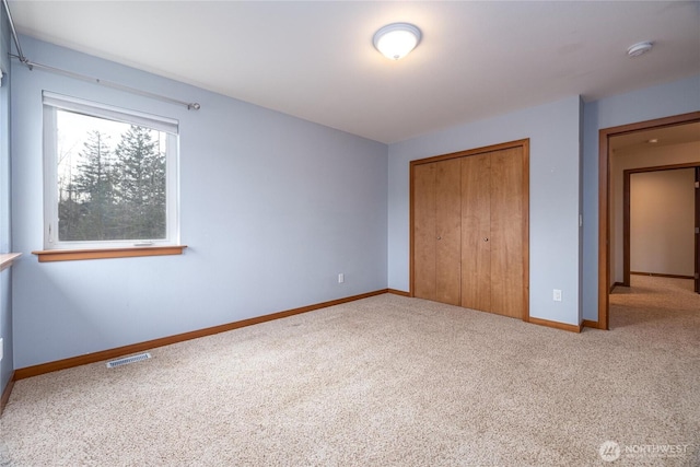 unfurnished bedroom with a closet, carpet, visible vents, and baseboards