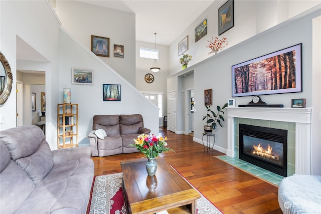 living room featuring a fireplace, a high ceiling, and wood-type flooring