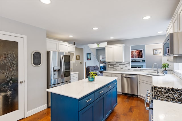 kitchen with a center island, white cabinets, blue cabinets, dark hardwood / wood-style floors, and appliances with stainless steel finishes